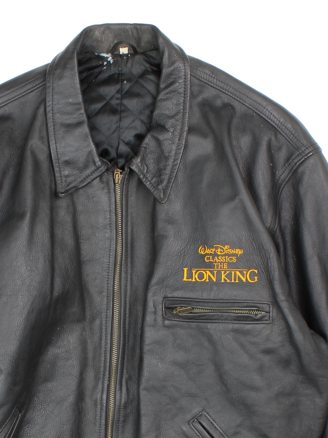 Vintage 1994 Disney Lion King Promo Leather Jacket in black. The jacket has a dagger collar, Lion King logo embroidered on the front panel and an interior pocket. The jacket is also lined with a quilted satin fabric. 