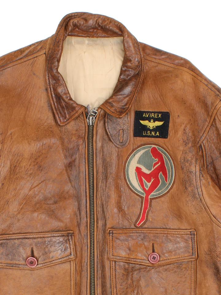 Vintage Avirex Flight Aviator Bomber Jacket in a brown colourway, zip up with side pockets and has badges embroidered on the front alongside the Avirex logo. 