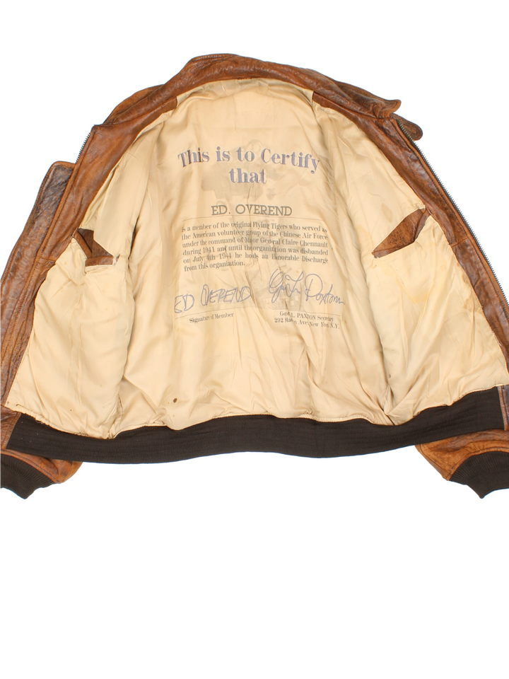 Vintage Avirex Flight Aviator Bomber Jacket in a brown colourway, zip up with side pockets and has badges embroidered on the front alongside the Avirex logo. 