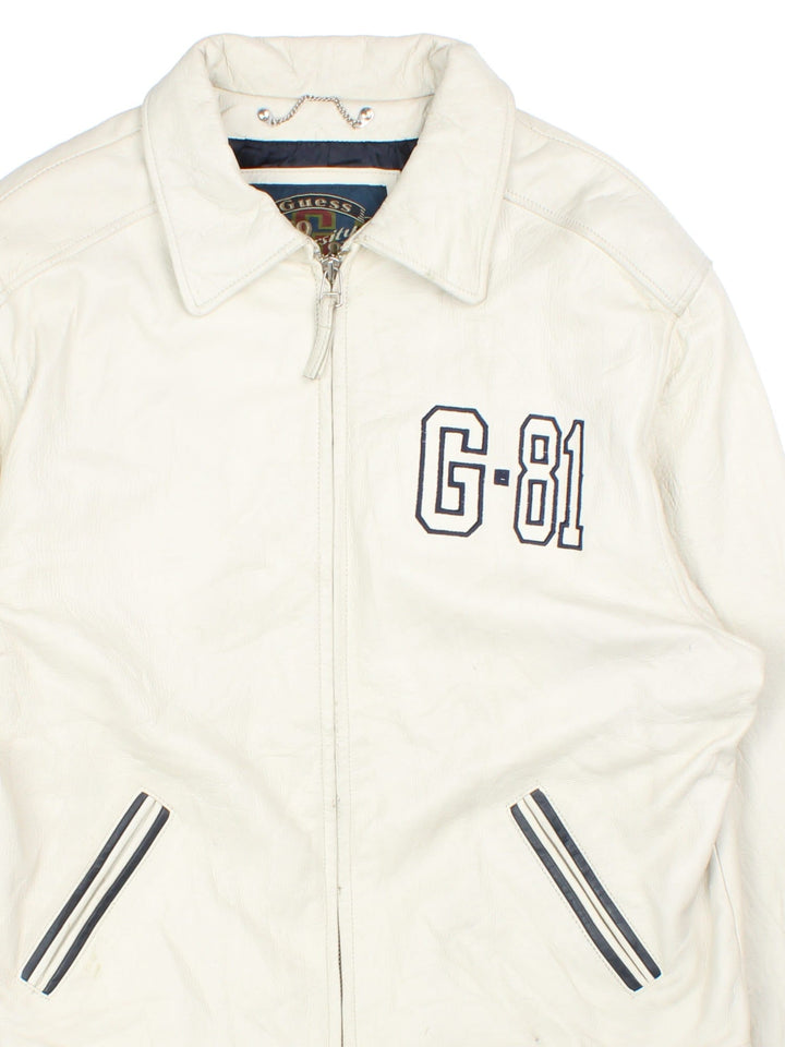 Vintage Guess 1981 Leather Jacket in a tan colourway. Full zip up with double pocket on the front. Varsity style lettering on the front and graphic on the back.