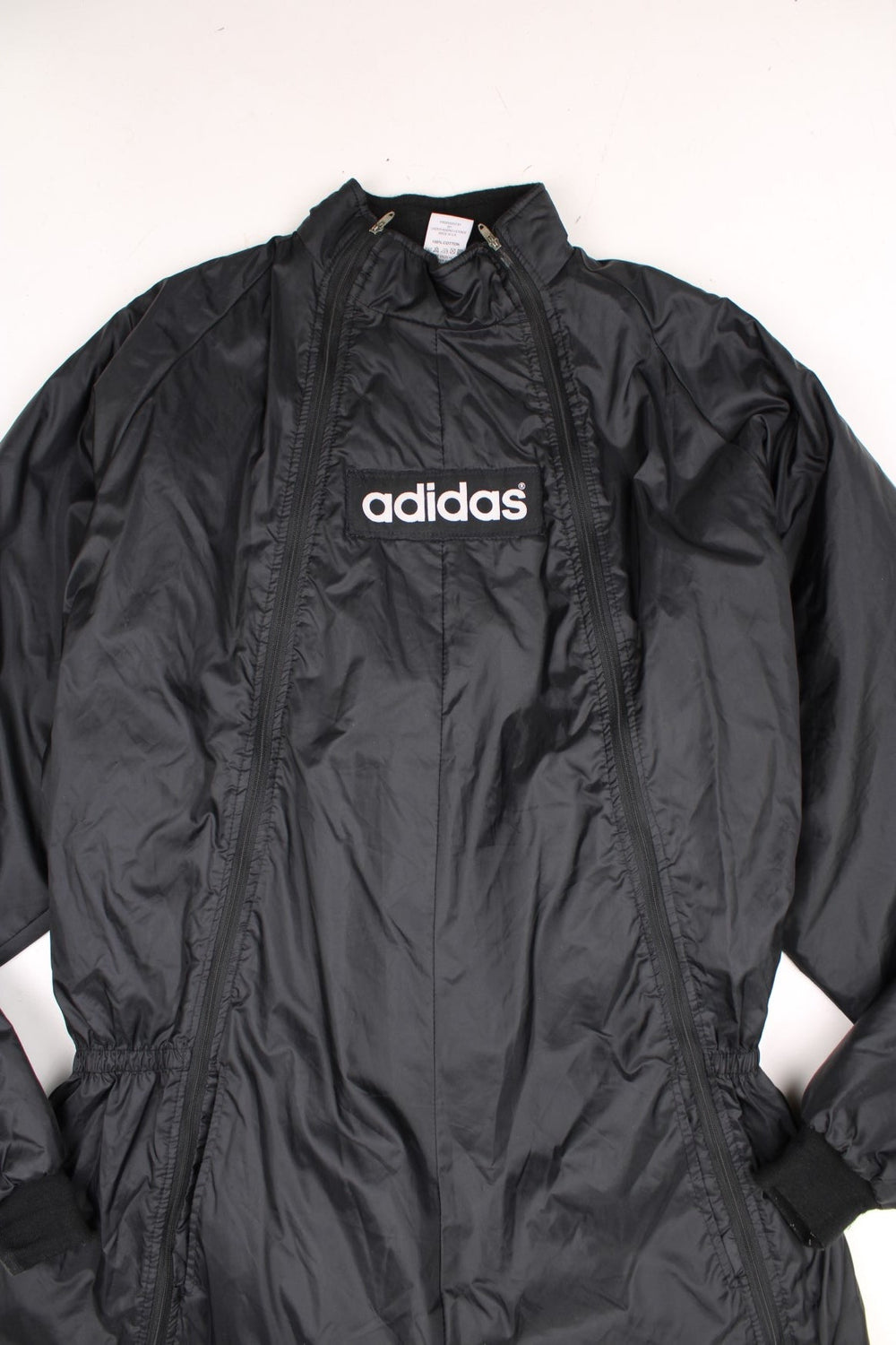 Adidas Jumpsuit in a black colourway, full zip down with side pockets, quilted lining, and has the spell out logo embroidered across the front and back. 