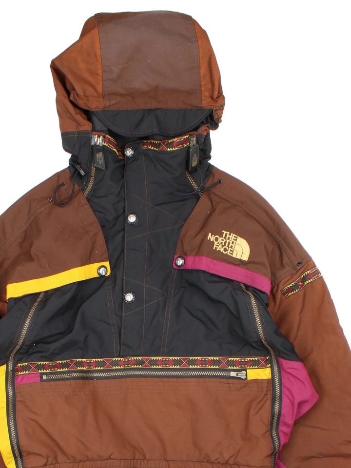 The North Face TNF Rage Series Ski Suit  in black/brown colourway with multiple pockets, some slight padding, elasticated waistband. Embroidered branding on the front and back.