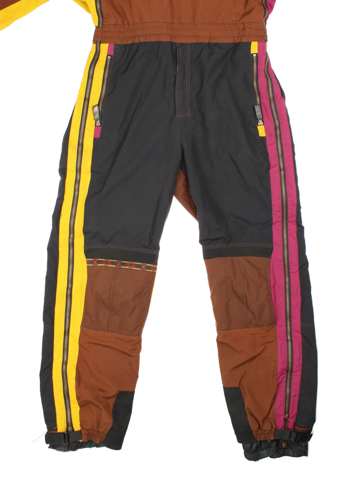 The North Face TNF Rage Series Ski Suit  in black/brown colourway with multiple pockets, some slight padding, elasticated waistband. Embroidered branding on the front and back.