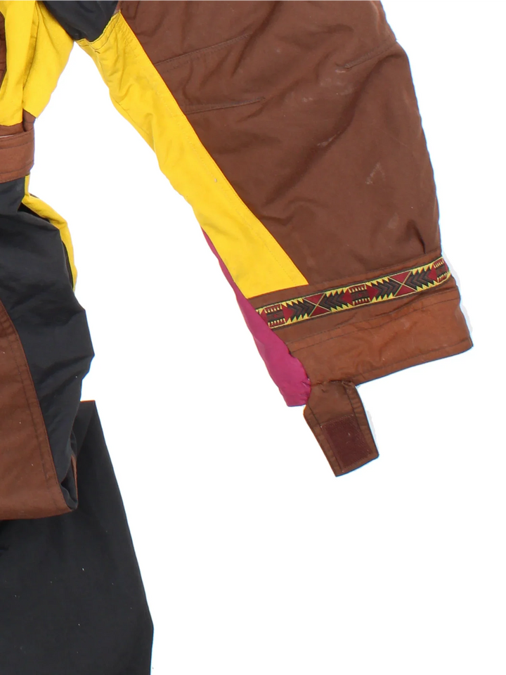 The North Face TNF Rage Series Ski Suit  in black/brown colourway with multiple pockets, some slight padding, elasticated waistband. Embroidered branding on the front and back.