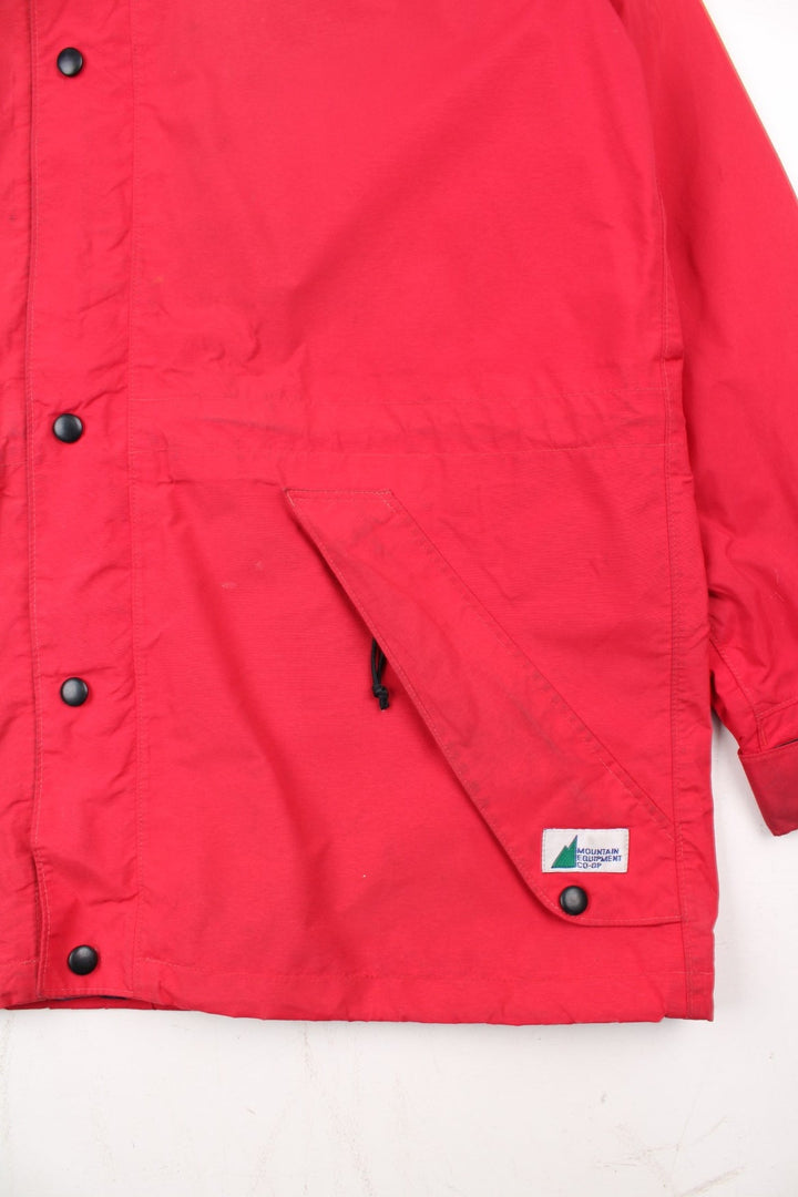 Vintage Mountain Equipment Jacket in a red colourway. Zips up and has side pockets, hooded, and has the logo embroidered on the front by the hem.