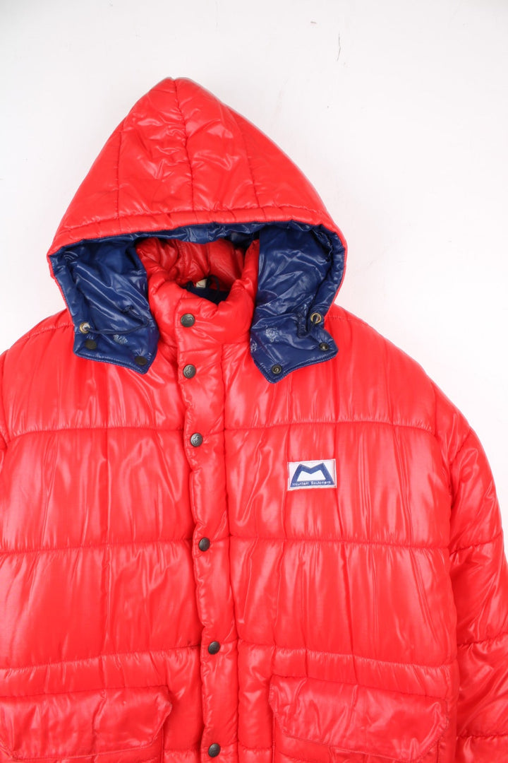 Vintage 80's Mountain Equipment Cerro Torre Puffer Coat in a red colourway. Zips and buttons up, has double front pockets, insulated lining, detachable hood, and has the logo embroidered on the front.