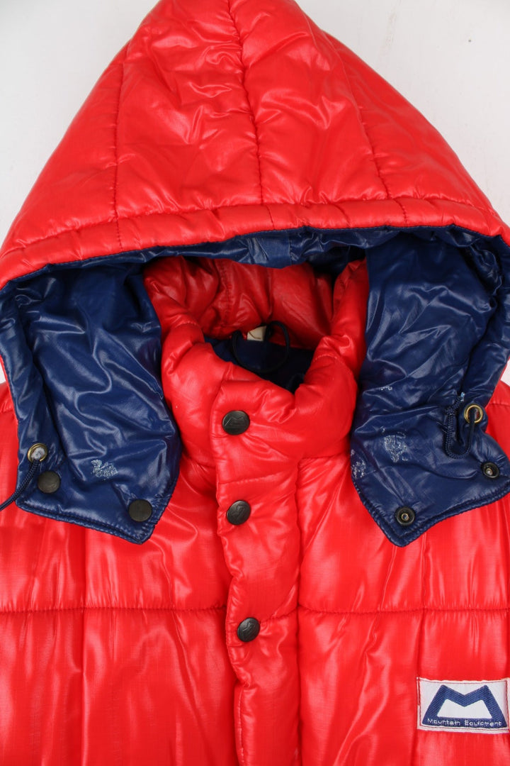 Vintage 80's Mountain Equipment Cerro Torre Puffer Coat in a red colourway. Zips and buttons up, has double front pockets, insulated lining, detachable hood, and has the logo embroidered on the front.