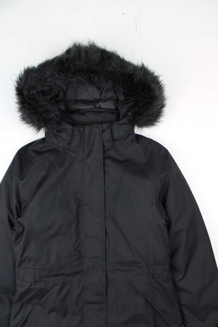 The North Face Jacket in a black colourway. Zips up and has side pockets, insulated lining, hooded with a faux fur trim, and has the logos embroidered on the left sleeve.