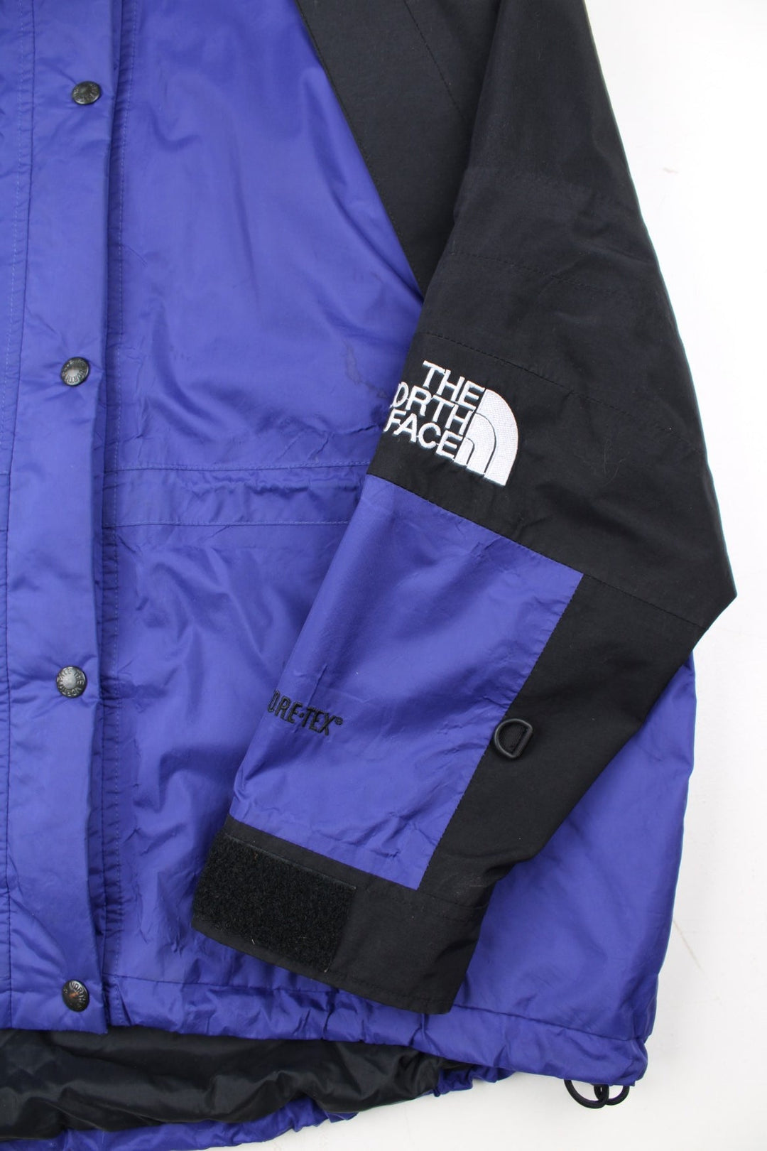 Vintage The North Face Mountain Light Jacket in a purple and black colourway. Zips and buttons up, has side pockets, hooded, and has the logo embroidered on the left sleeve.