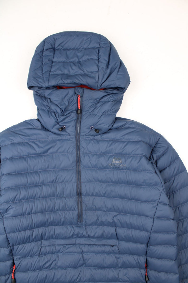 Mountain Equipment Earthrise Down Jacket in a blue colourway. Half zip pullover jacket, has two front pouch pockets, insulated lining, hooded, and has the logo printed on the front.