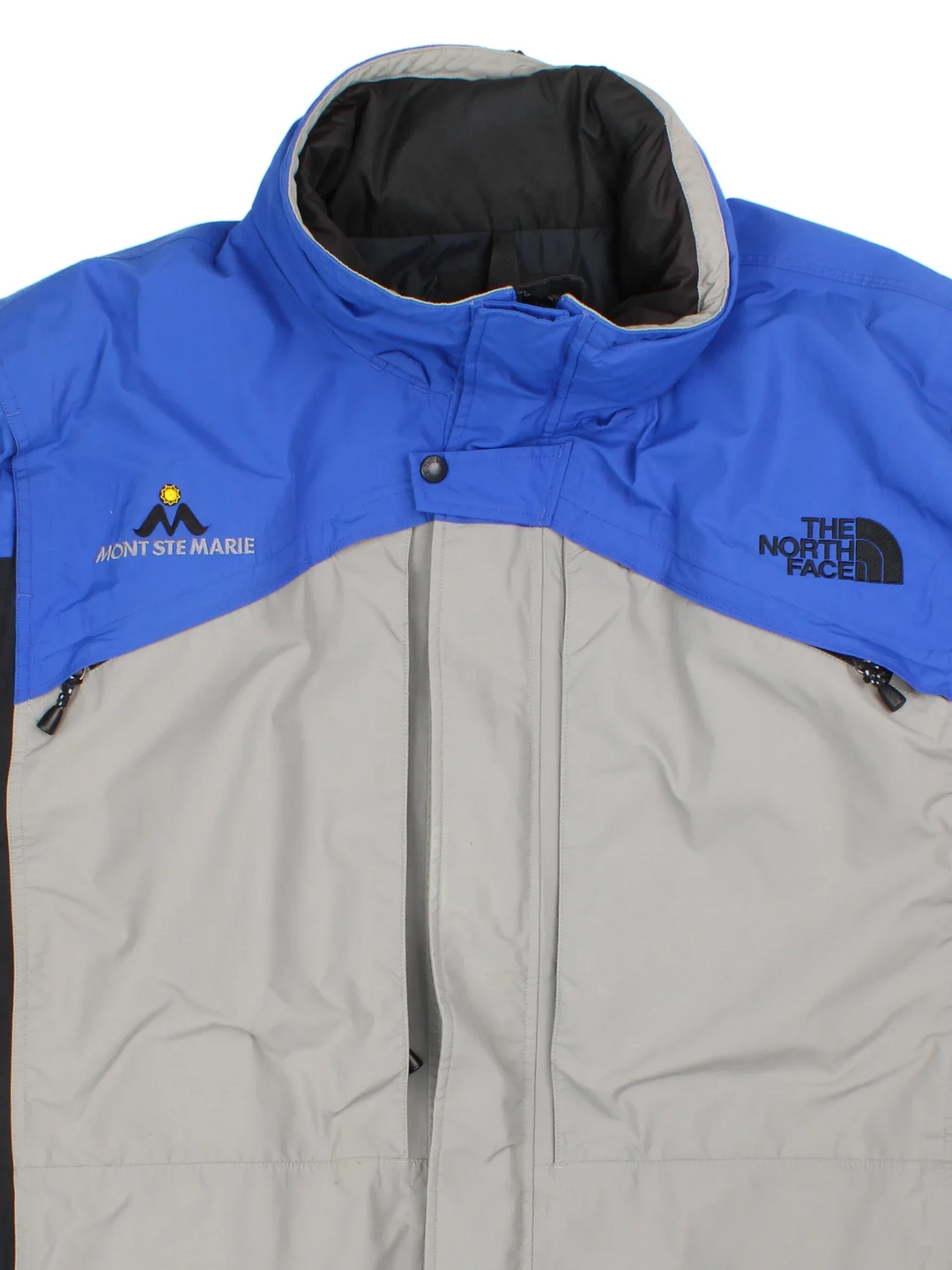 Vintage The North Face Mountain Ski Jacket in a blue/grey colourway. Zip fastening with hood and multiple zip pockets. Drawstring hem, mesh lining and has the logo embroidered on the front/back.