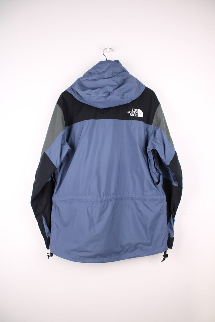 The North Face Hydroseal blue and grey zip through waterproof jacket. Features multiple pockets, foldaway hood and embroidered logo on the sleeve