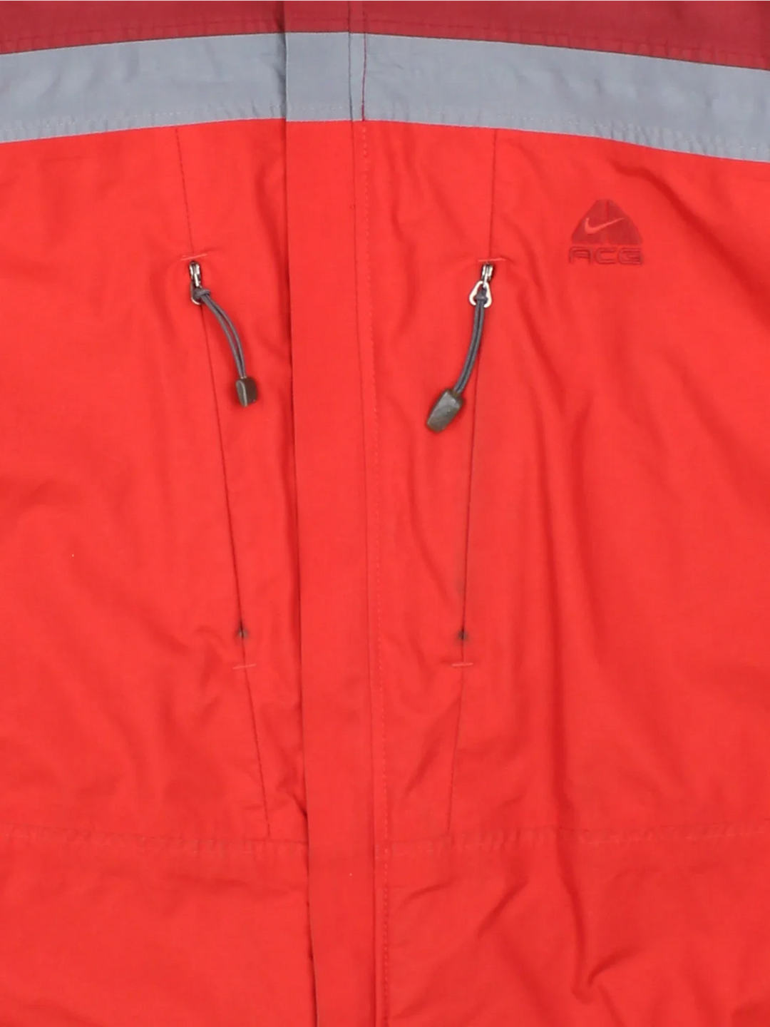 Nike ACG Coat in a red colourway with contrasting red and grey panelling. full zip up, hood and has multiple pockets, classic logo embroidered on the front.