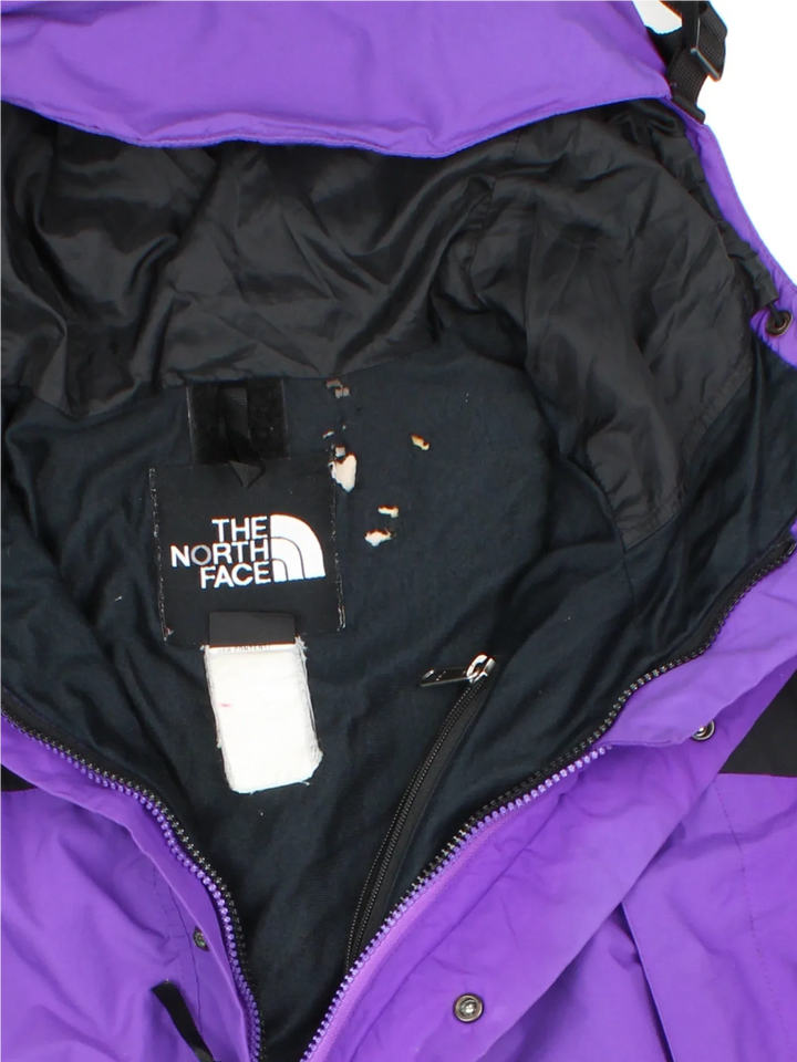 The North Face Gore-Tex Mountain Jacket in a purple colourway with black panelling, full zip up and button up. multiple pockets, hood, drawstring hem and has the logo embroidered on the sleeve and front.