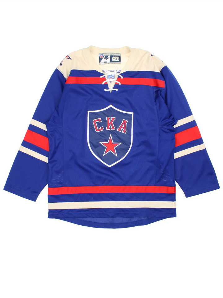 SKA St.Petersburg Vintage Ice Hockey Jersey in a blue colourway with red and white stripe detailing. Features embroidered logos and badge on the front with lace up around the collar.