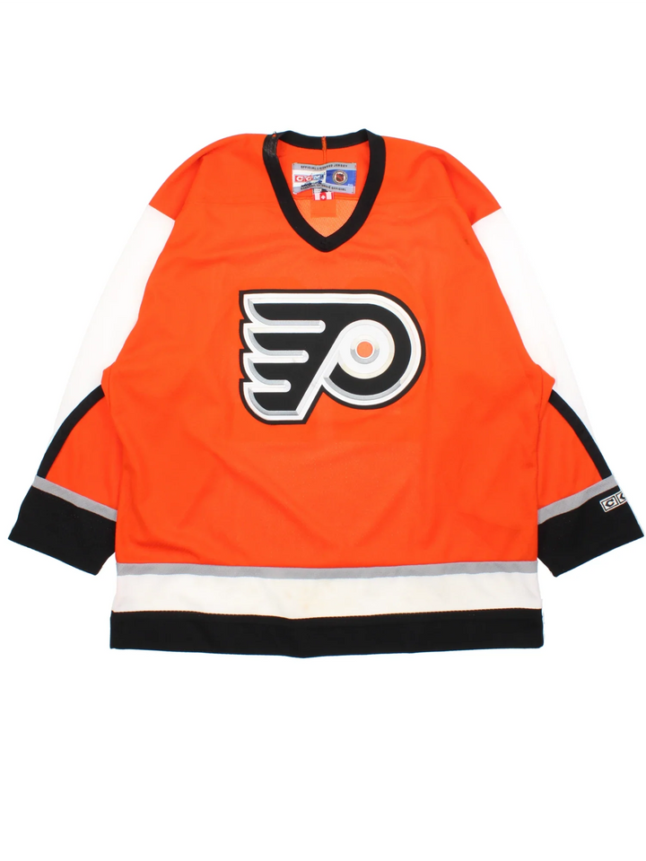 Philadelphia Flyers NHL Jersey in a  orange colourway, features embroidered logos and badge on the front with black and white stripe detailing on the sleeves and hem.