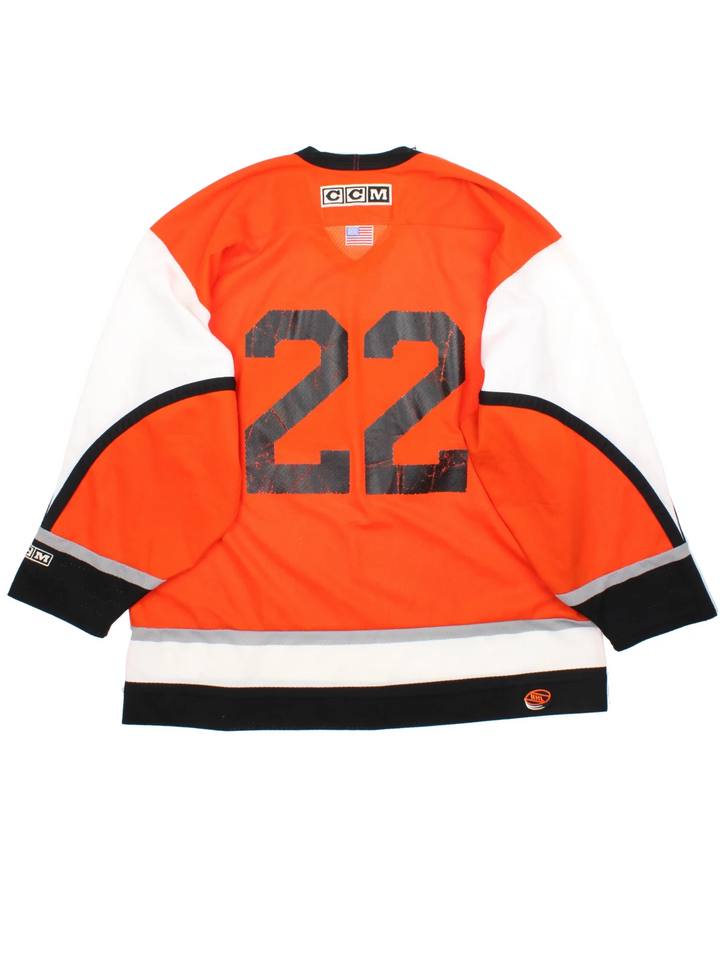 Philadelphia Flyers NHL Jersey in a  orange colourway, features embroidered logos and badge on the front with black and white stripe detailing on the sleeves and hem.