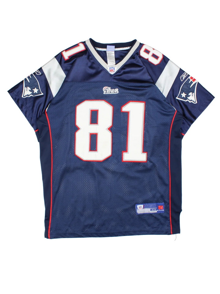 New England Patriots Reebok NFL Jersey in the blue home kit colourway with silver and red detailing, features embroidered logos and badge on the front and player name MOSS #81 on the back.