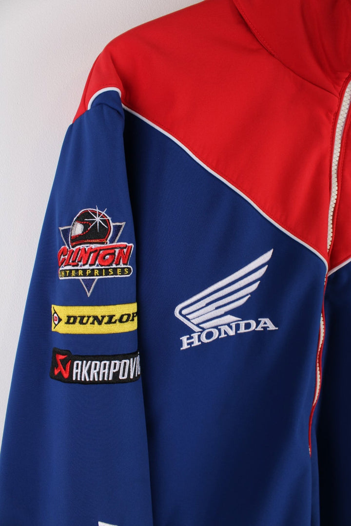  Honda Softshell Racing Jacket in a  and red colourway, zips up and has side pockets, hidden hood, and the logos embroidered all over the jacket.