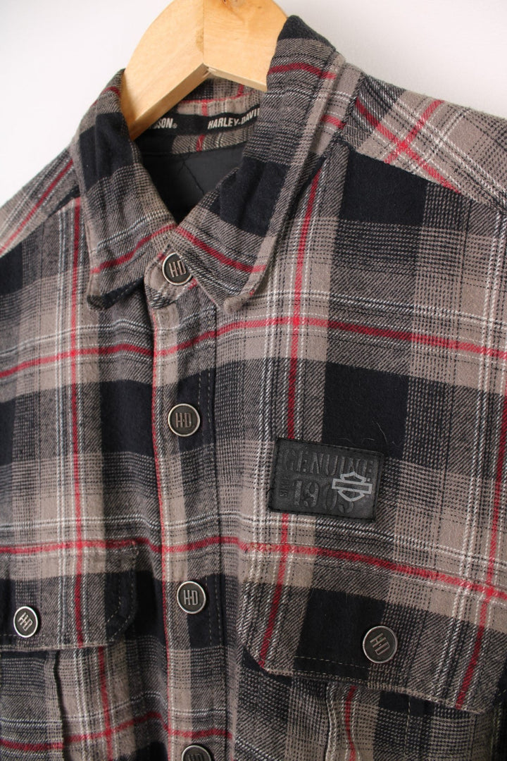  Flannel Style Shacket in a , black and red plaid colourway, buttons up, has multiple pockets, quilted lining and the logo embroidered on the front and back.