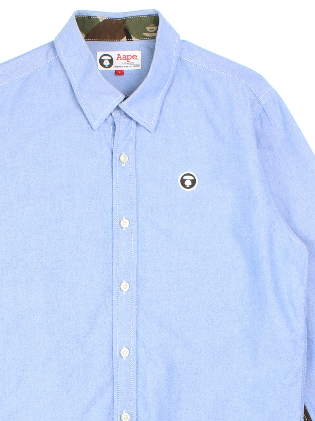 A Bathing Ape By Bape Oxford Shirt in a blue colourway and has camo panelling by on the sleeves, button up with the logo embroidered on the front.