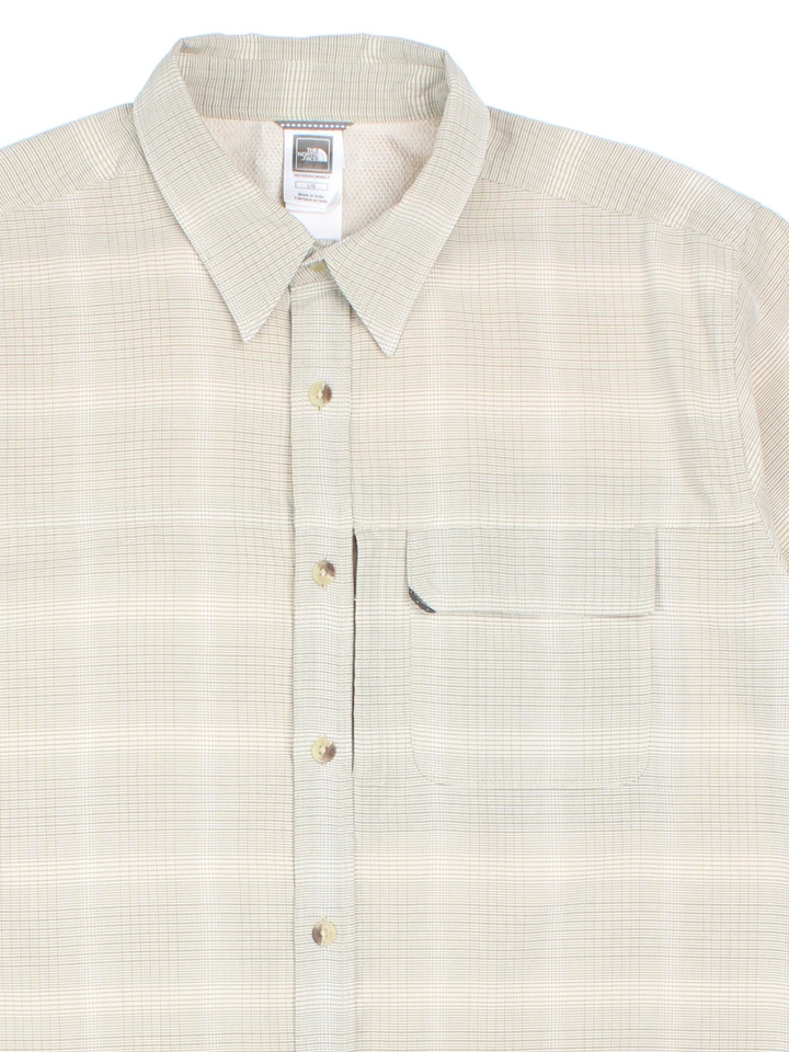 The North Face Shirt in a tan colourway and plaid pattern all over, button up and has a chest pocket with the logo embroidered on the front.