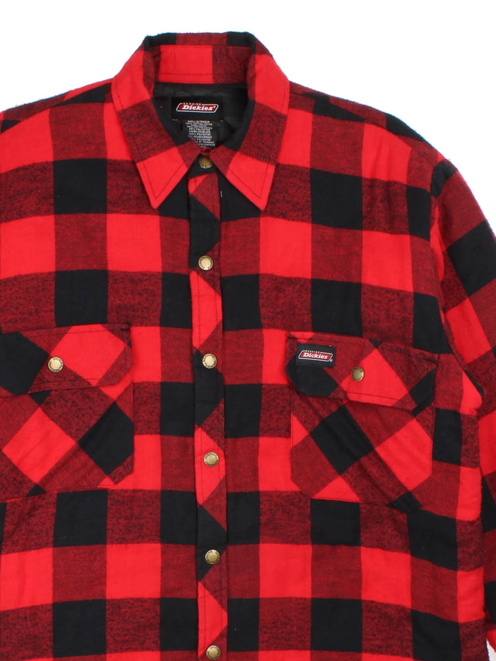 Dickies Flannel Jacket in a red and black checkered colourway. Buttons up and has double chest pockets, insulated with a quilted lining, and has the logos embroidered on the front.