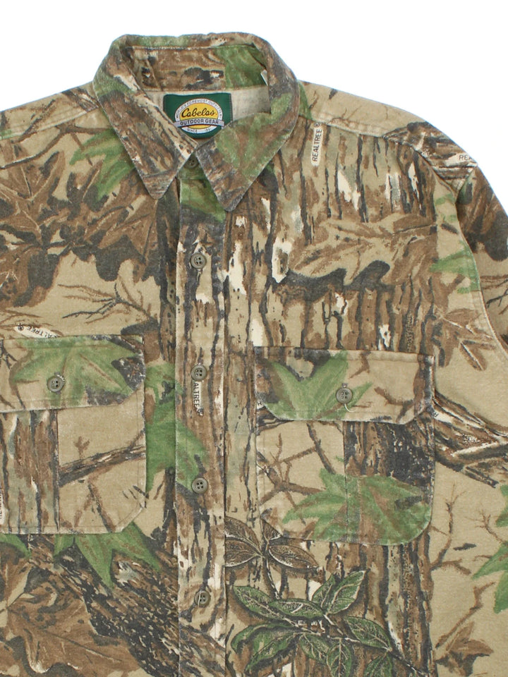 Vintage Cabelas Real Tree Camo Shirt in a green and brown patterned colourway, buttons up and has double chest pockets on the front.
