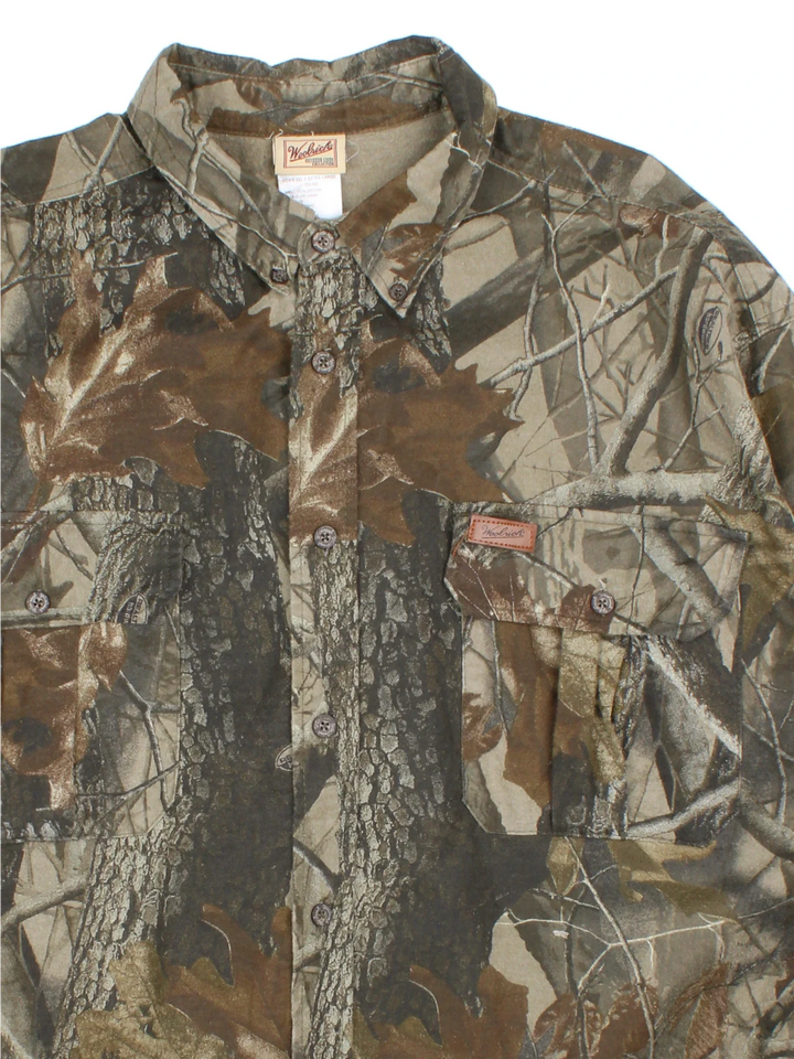 Woolrich Real Tree Camo Shirt in a green and brown colourway, button up and has double chest pockets with the logo embroidered on the front.