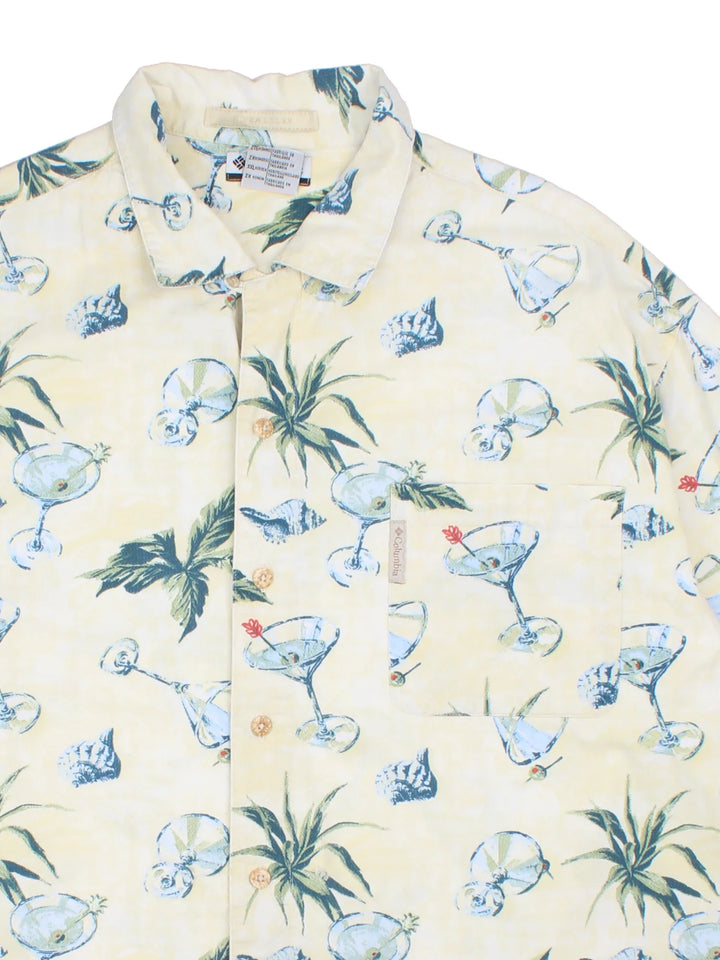 Columbia Hawaiian Shirt in a tan colourway with floral and cocktail all over print, button up and has a chest pocket with the logo embroidered on.