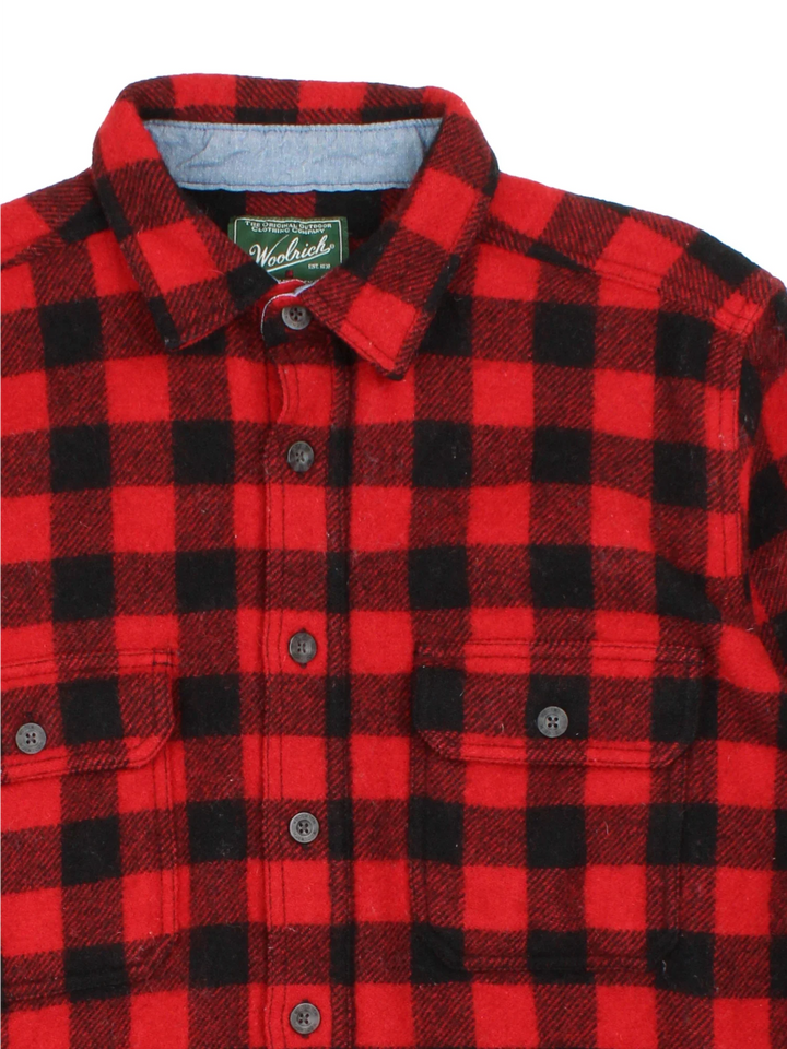 Woolrich Flannel Shirt in a red and black colourway with all over plaid pattern. button up with two pockets on the front.