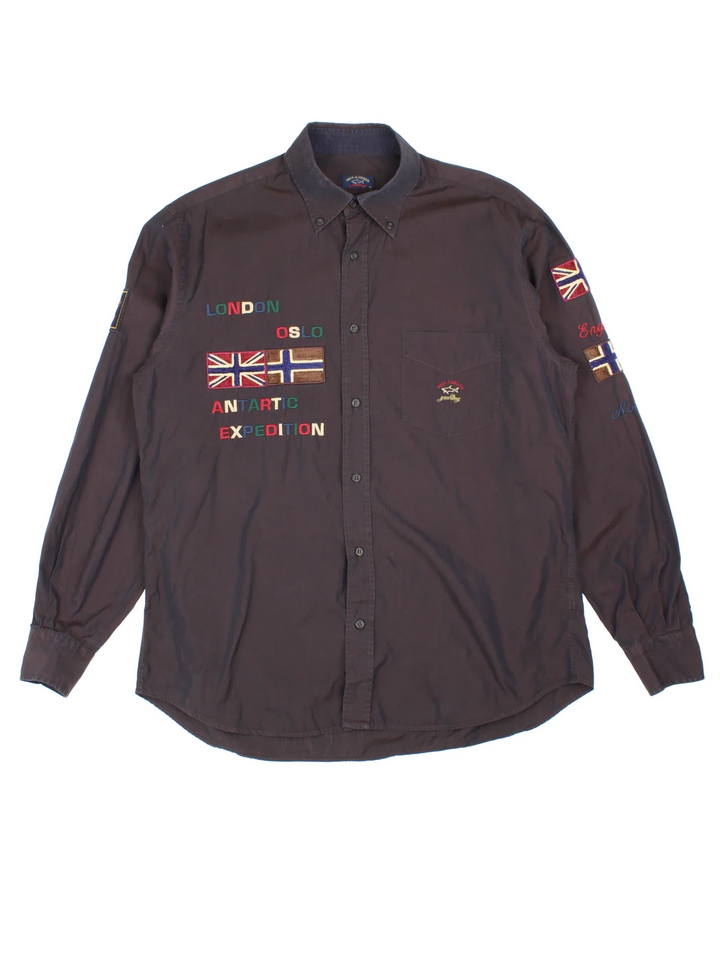 Paul & Shark Yatch Sailing Shirt in a black colourway, button up and has a chest pocket with the logo embroidered on the front alongside text and flags on the front, back and sleeves.