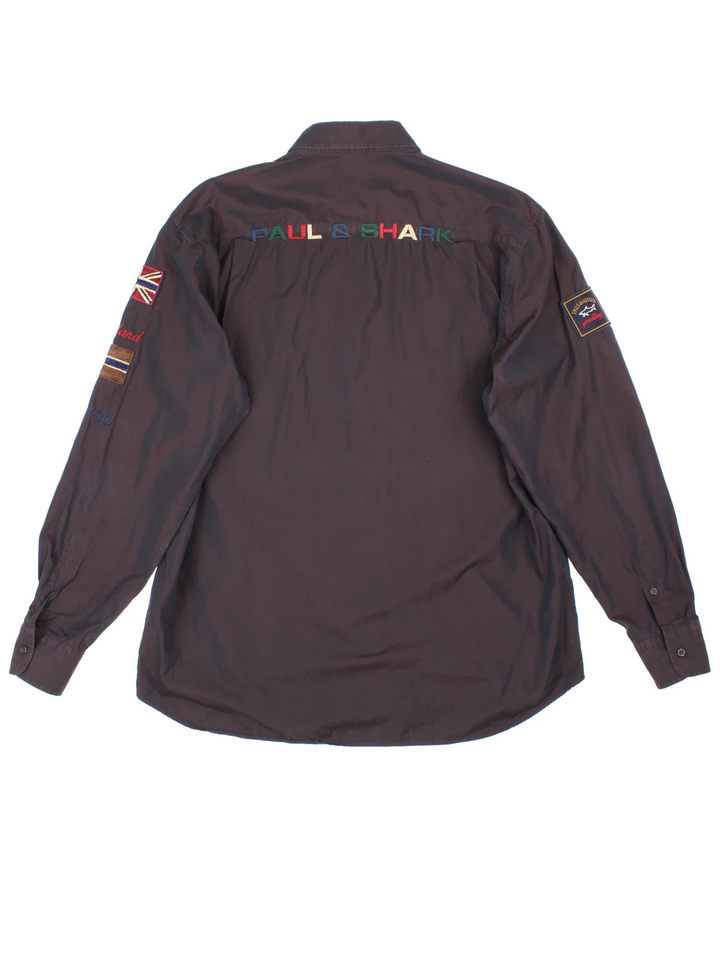 Paul & Shark Yatch Sailing Shirt in a black colourway, button up and has a chest pocket with the logo embroidered on the front alongside text and flags on the front, back and sleeves.