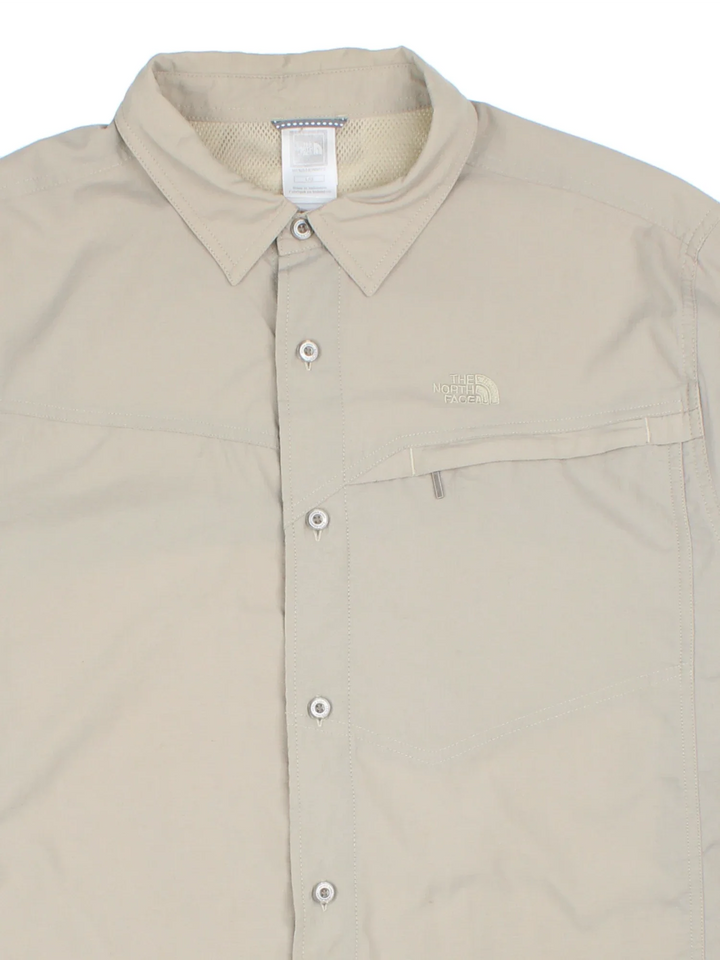 The North Face Ripstop Shirt in a tan colourway, button up and has a chest pocket with the logo embroidered on the front.