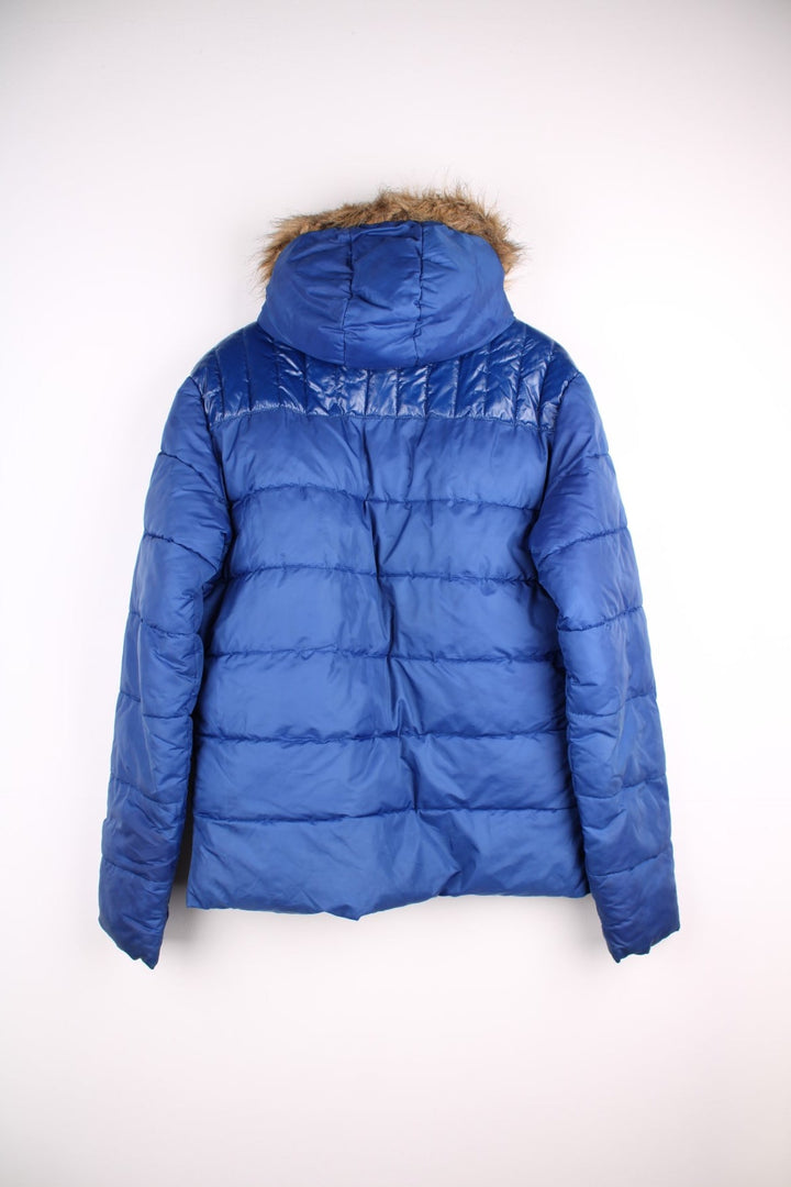 Y2K Ellesse Coat in a blue colourway, the coat has a faux fur trim hood, is filled with a polyester filling and has two hand warmer pockets on the front panels. There is an Ellesse Ski patch sewn onto the front and Ellesse embroidered on the sleeve. 