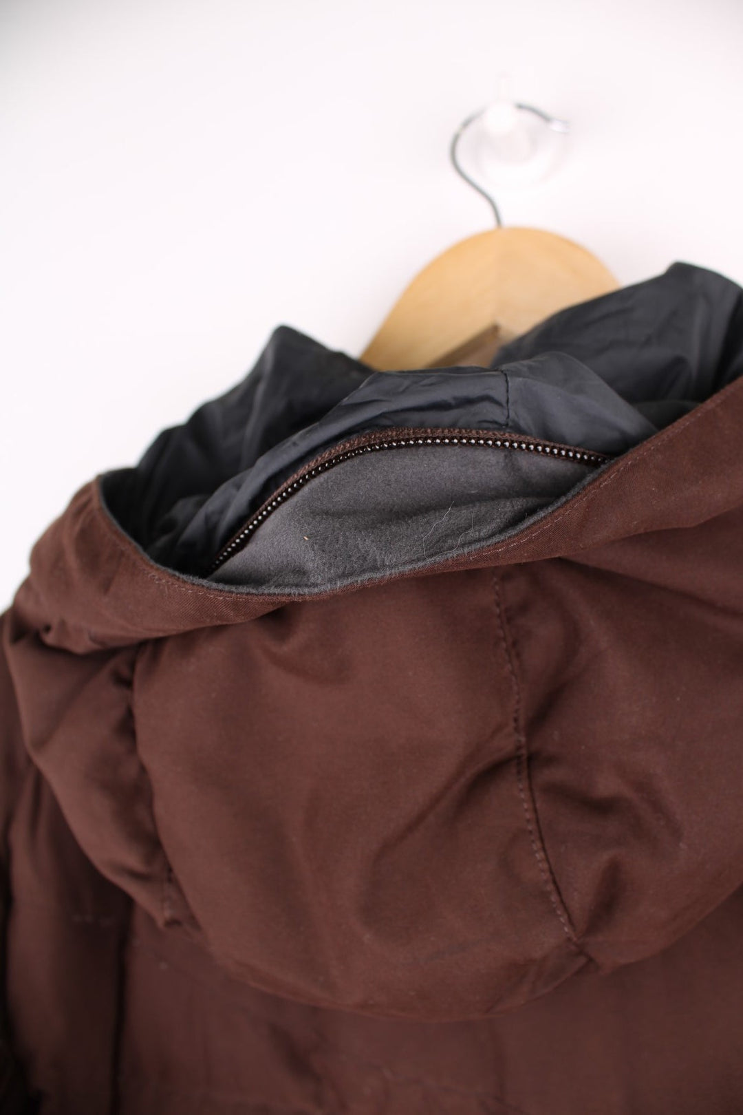 The North Face Puffer jacket in brown. The jacket is filled with duck down feathers, has two pockets on the front panels and a puffer hood. There is an interior pocket, and elasticated cuffs and hem. 