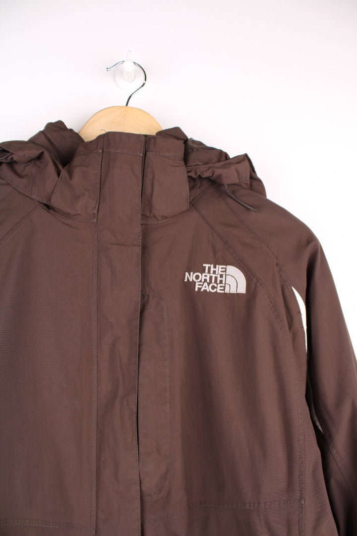 The North Face Waterproof coat in brown. The jacket has a removable fleece lining, multiple pockets, and a removable hood.