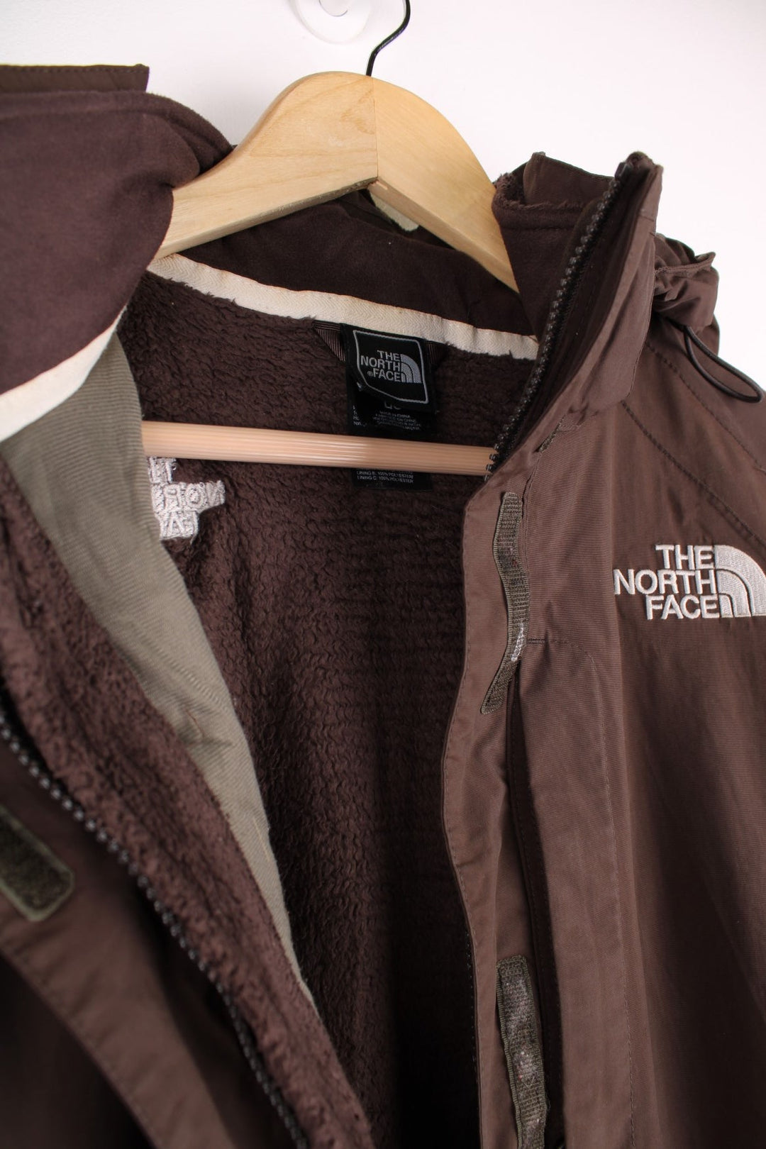The North Face Waterproof coat in brown. The jacket has a removable fleece lining, multiple pockets, and a removable hood.