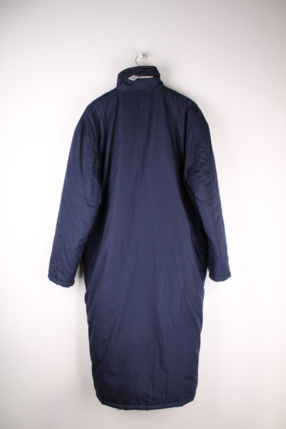 Vintage 1990s Umbro Coat in a navy blue colourway. The coat has multiple Umbro logos embroidered on the collar and sleeves and has two top pockets and two bottom pockets on the front. 