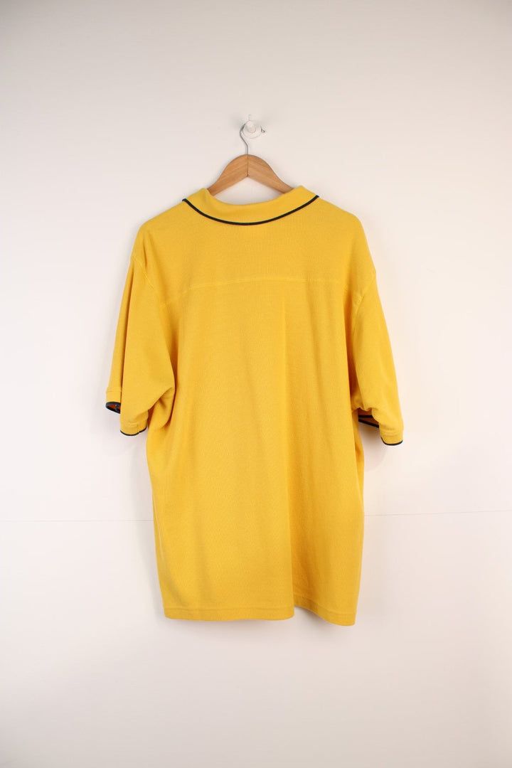Umbro Polo Shirt in a yellow colourway with navy stripes going round the end of the cuffs and collar, button up, and has the logo embroidered on the front.