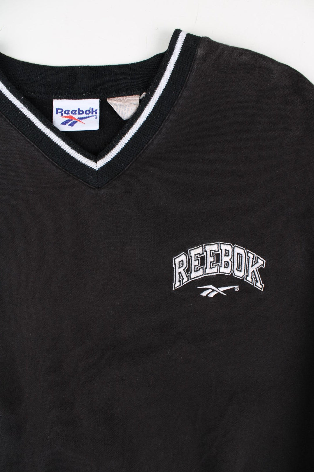Vintage Reebok Drill Training Top in a black colourway with stripe detailing around the neck and cuffs. Small vintage logo on the chest.