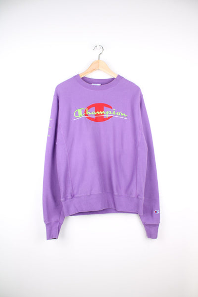 Purple Champion Reverse Weave sweatshirt with red and green embroidered logo across the chest and on the sleeve. 