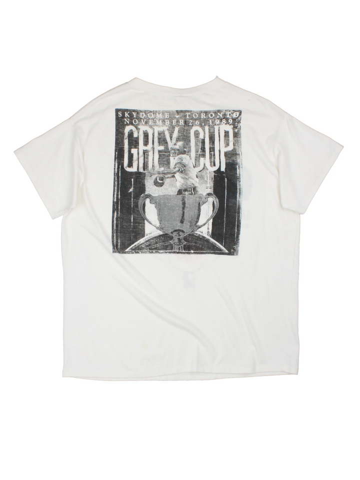 Vintage 1989 CFL Grey Cup Saskatchewan Roughriders vs Hamilton Tiger Cats tee in white with helmet face-off graphic on the front and photo of trophy on the back.