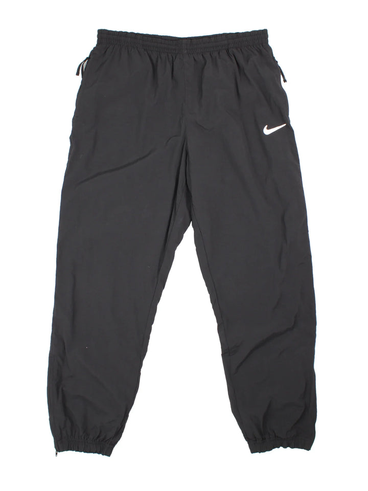 90's Nike Tracksuit Bottoms in black colourway. Side pockets, elasticated waist and the logo embroidered on the front.