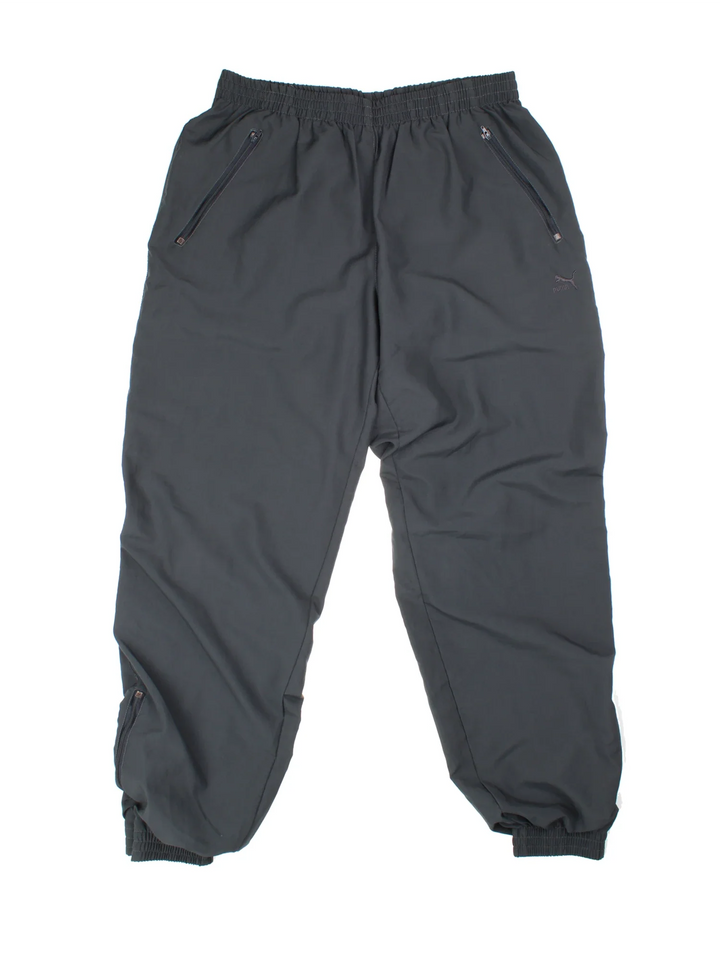 90's Puma Tracksuit Bottoms in black colourway with cuffed hem. Zipper ankle leg, side zip pockets and the logo embroidered on the front.