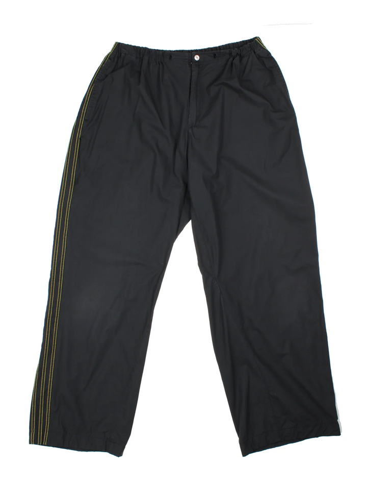 Adidas Shell Trousers in a black colourway with iconic three stripes going down the sides, has multiple pockets, elasticated waist. high waisted, and the logo printed on the back.