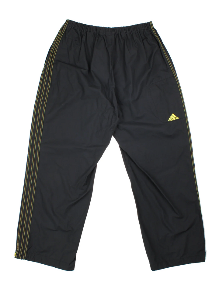 Adidas Shell Trousers in a black colourway with iconic three stripes going down the sides, has multiple pockets, elasticated waist. high waisted, and the logo printed on the back.