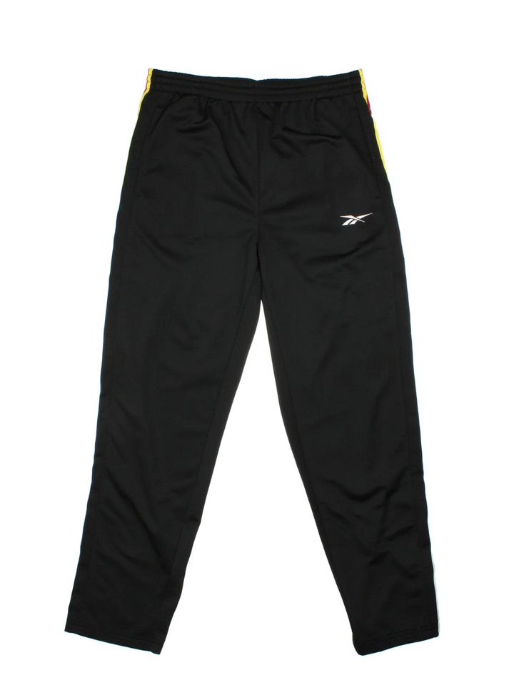 Reebok Popper Tracksuit Bottoms in a black colourway with yelow and red stripes going down the sides alongside popper button openings, has pockets, elasticated waist with drawstring, and the logo embroidered on the front.