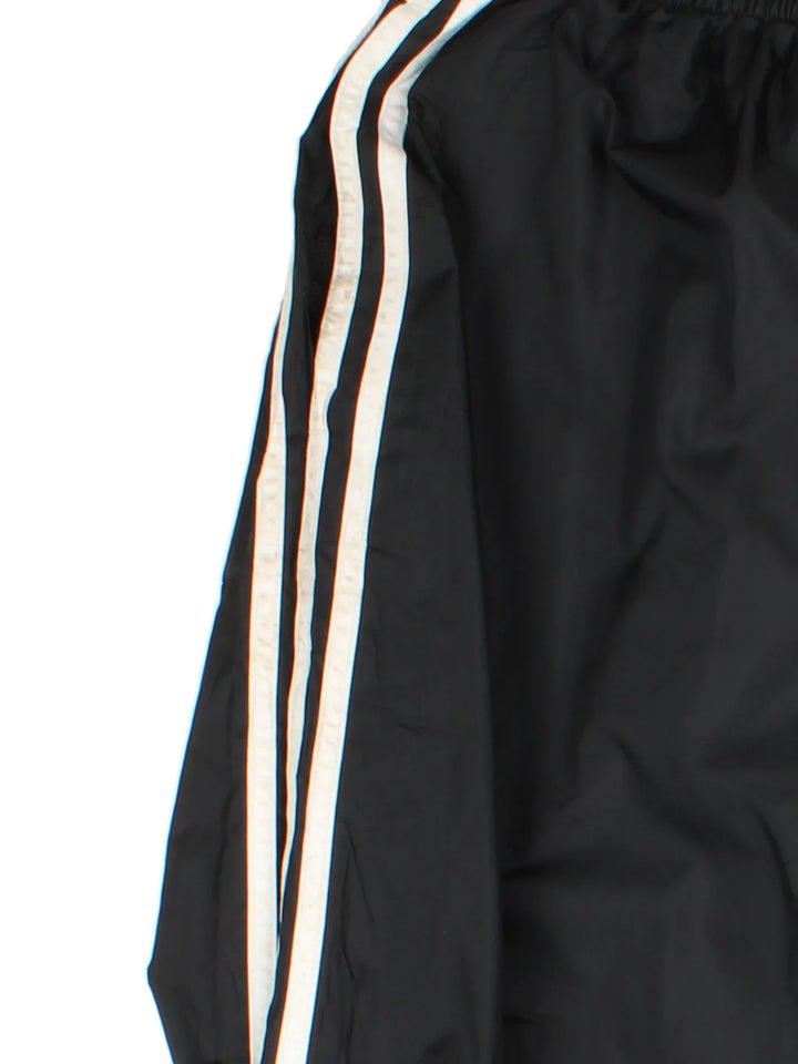 Vintage Adidas Tracksuit Bottoms in a black colourway with the iconic three stripes down the sides, has pockets, adjustable velcro straps by the cuffs, mesh lining, and the logo embroidered on the front.