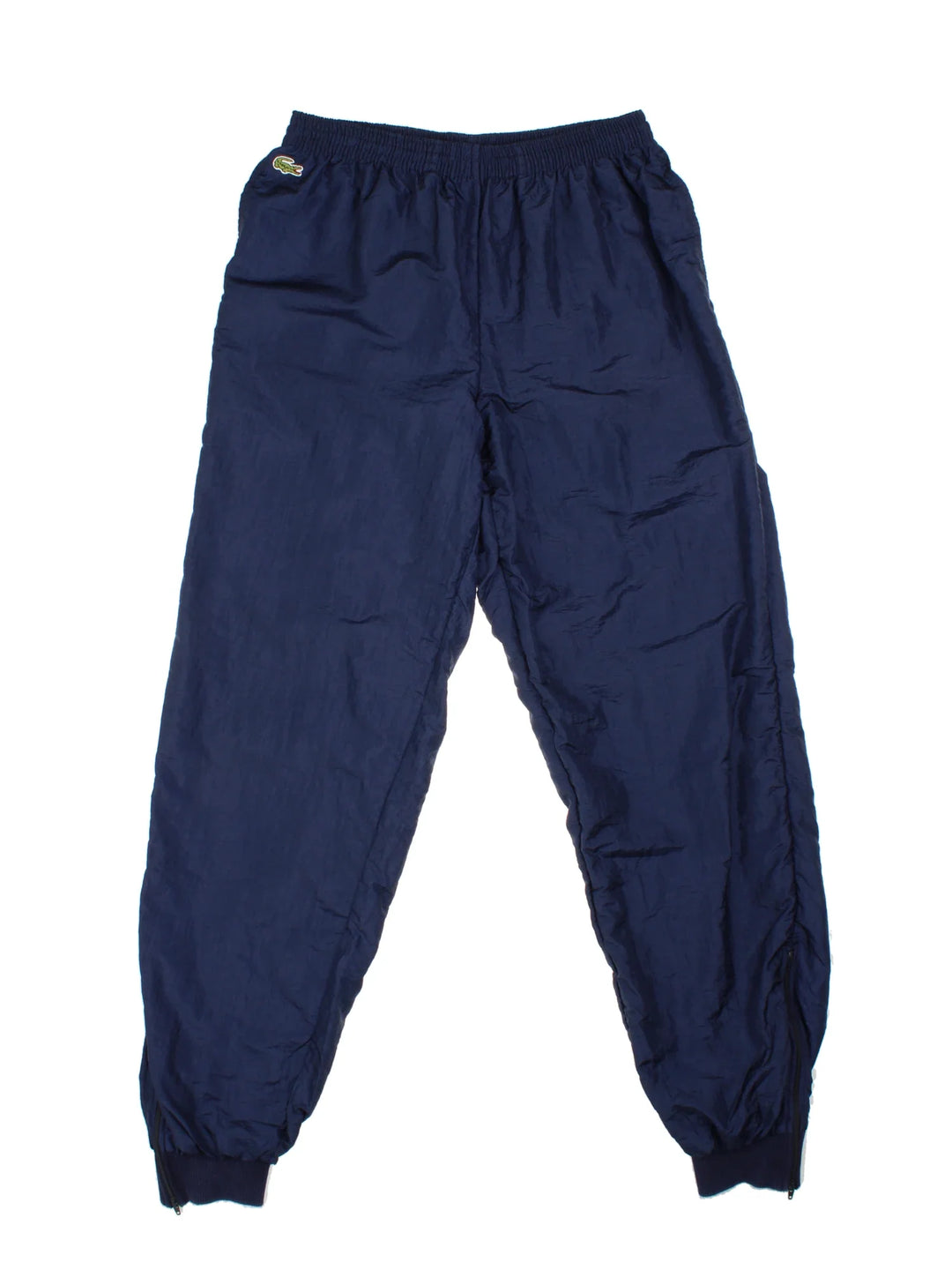 Vintage Lacoste Shell Pants in a blue colourway with pockets, elasticated waist with drawstring, cotton lining and the logo embroidered on the front.